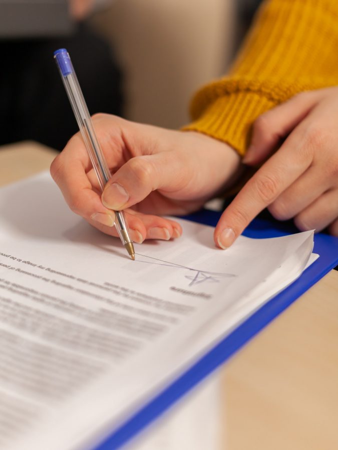 Businesswoman signing paper, partner hand puts signature on document